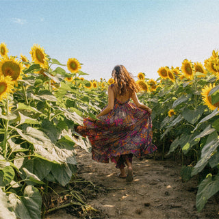 Person in a colorful dress runs through a field of sunflowers