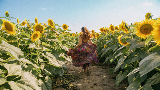 Person in a colorful dress runs through a field of sunflowers